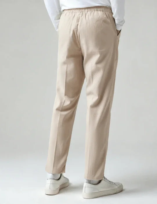 Back view of beige casual pants with elastic waistband, white sneakers, and white top