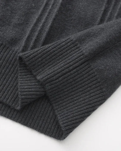Dark gray knit sweater sleeve with ribbed cuff detail on a white background