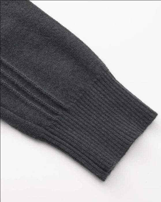 Dark gray knit sweater sleeve with ribbed cuff on white background
