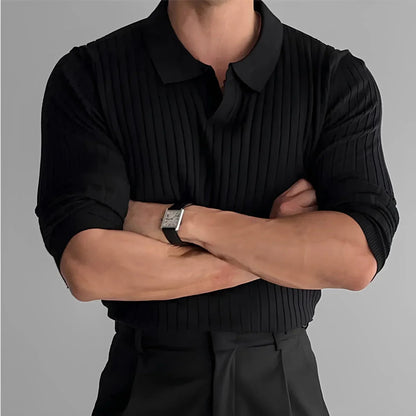Man wearing black ribbed sweater polo with folded arms, dress pants, and wristwatch